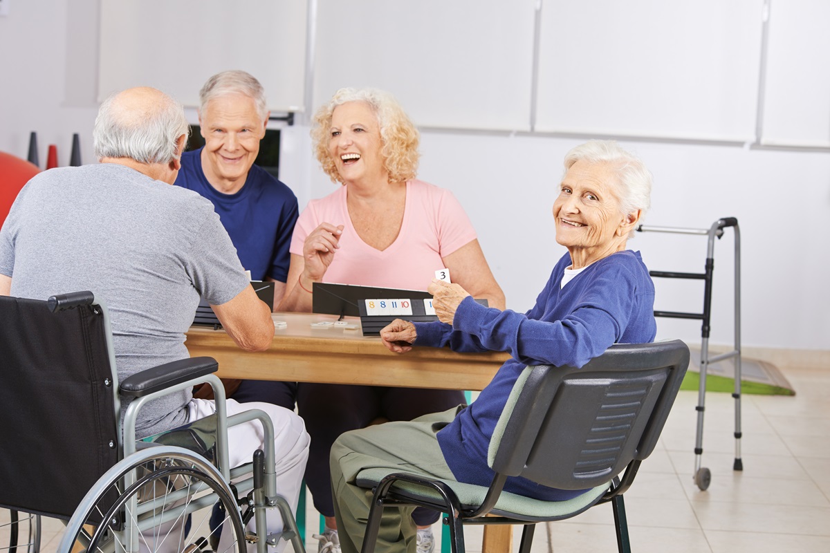 Mann im Rollstuhl mit anderen älteren Herrschaften im Gespräch am Tisch