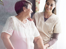 Pflegerin hilft einer Frau am Rollator