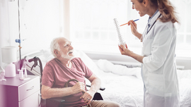 &Auml;lterer pflegebed&uuml;rftiger Mann am Pflegebett mit &Auml;rztin