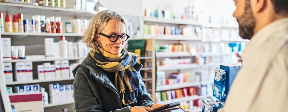Reife Frau zahl Medikamente in der Apotheke mit dem Handy