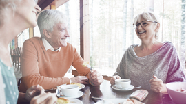 Drei Menschen lachend am Kaffeetisch