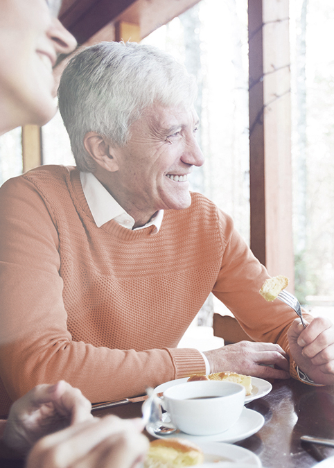 Drei Menschen lachend am Kaffeetisch