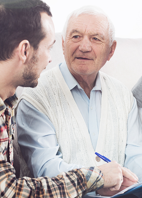 Ein j&uuml;ngerer Mann hilft einem &auml;lteren Herren beim Ausf&uuml;llen einer Betreuungsverf&uuml;gung