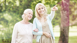 &Auml;ltere mit j&uuml;ngerer Frau, die auf etwas zeigt, beim Spaziergang durch einen Park