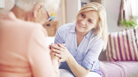 Pflegerin, die einer &auml;lteren Dame zuh&ouml;rt, in deren h&auml;uslichen Umgebung