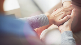 Ausschnitt, in dem eine Frau die Hand einer anderen Frau h&auml;lt