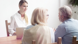 Ehepaar im mittleren Alter von hinten, das sich von einer jungen Frau beraten l&auml;sst