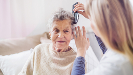 Pflegebed&uuml;rftige Frau bekommt von einer Pflegerin die Harre gek&auml;mmt