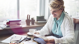Eine Frau am Tisch pr&uuml;ft verschiedene Unterlagen